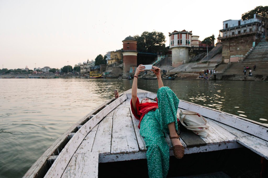Must Explore in 2025-Western woman lying on a boat taking selfies in Varanasi