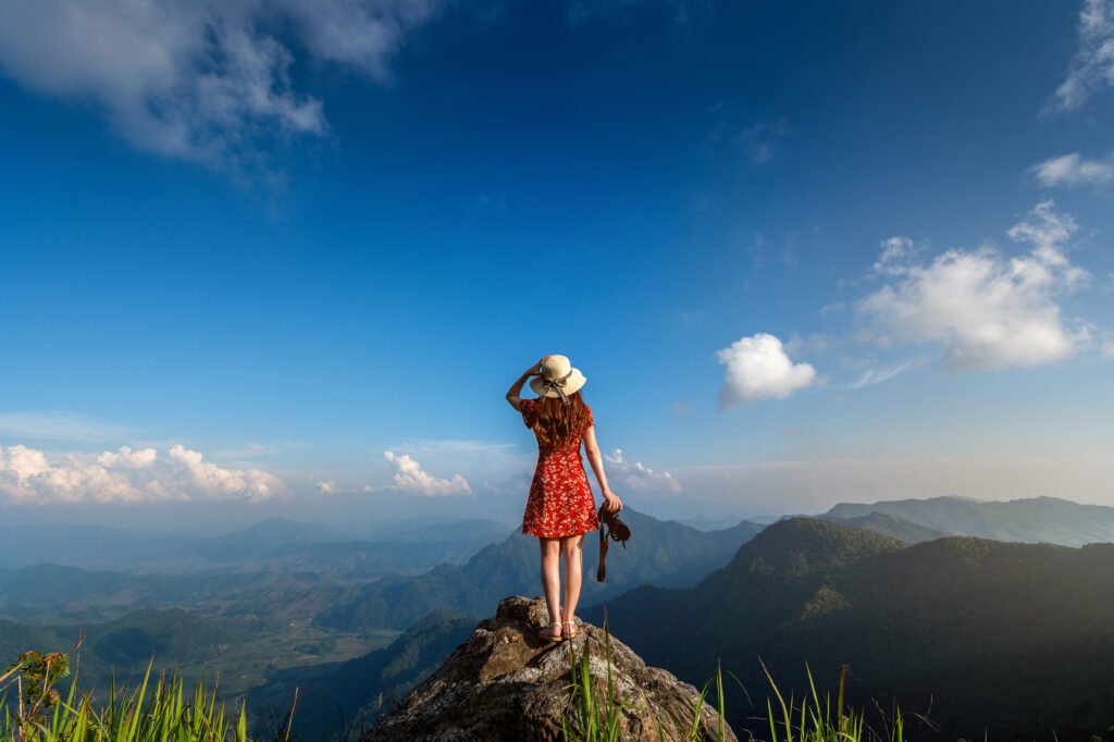 best places to travel-Woman hand holding camera and standing on top of the rock in nat