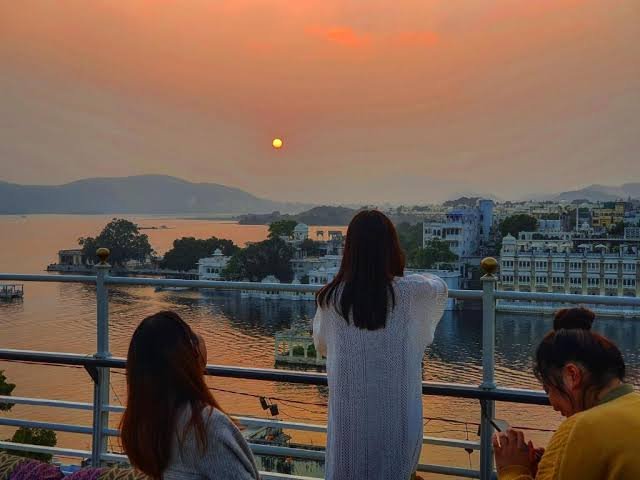Lake Pichola sunset view in Udaipur with budget hostel rooftops – affordable travel in Udaipur 2025