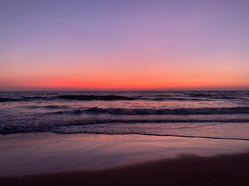 Peaceful sunset view over the ocean at Gokarna Beach, India, showcasing vivid colors and gentle waves.
