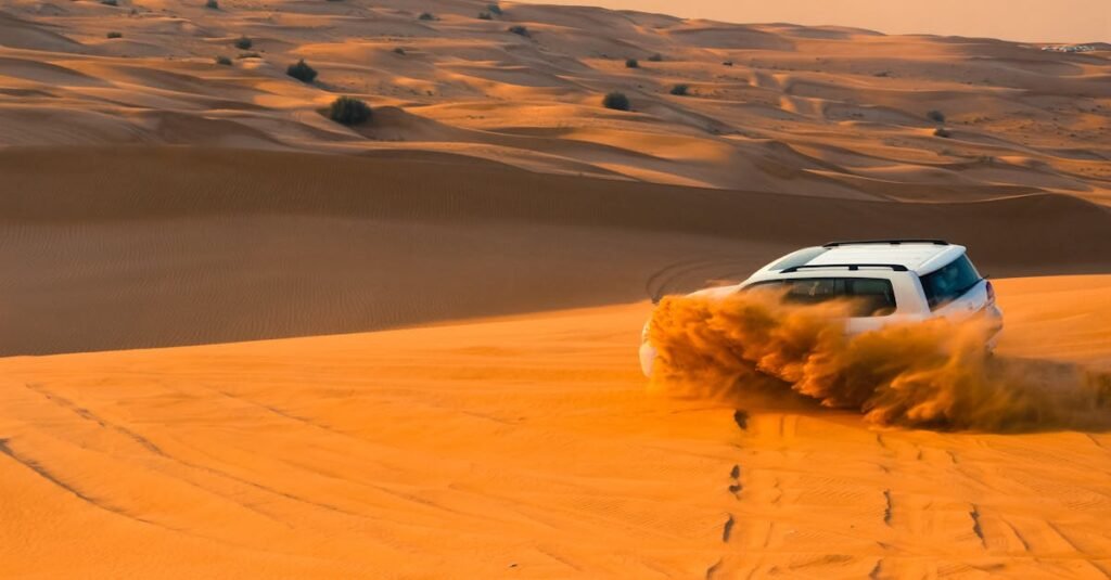 A thrilling SUV driving through the sand dunes of Dubai's desert landscape at sunset: Dubai tourist spots.