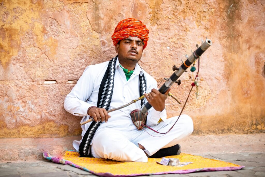 A Rajasthani musician plays the rawanhatta, showcasing cultural heritage against a textured wall.