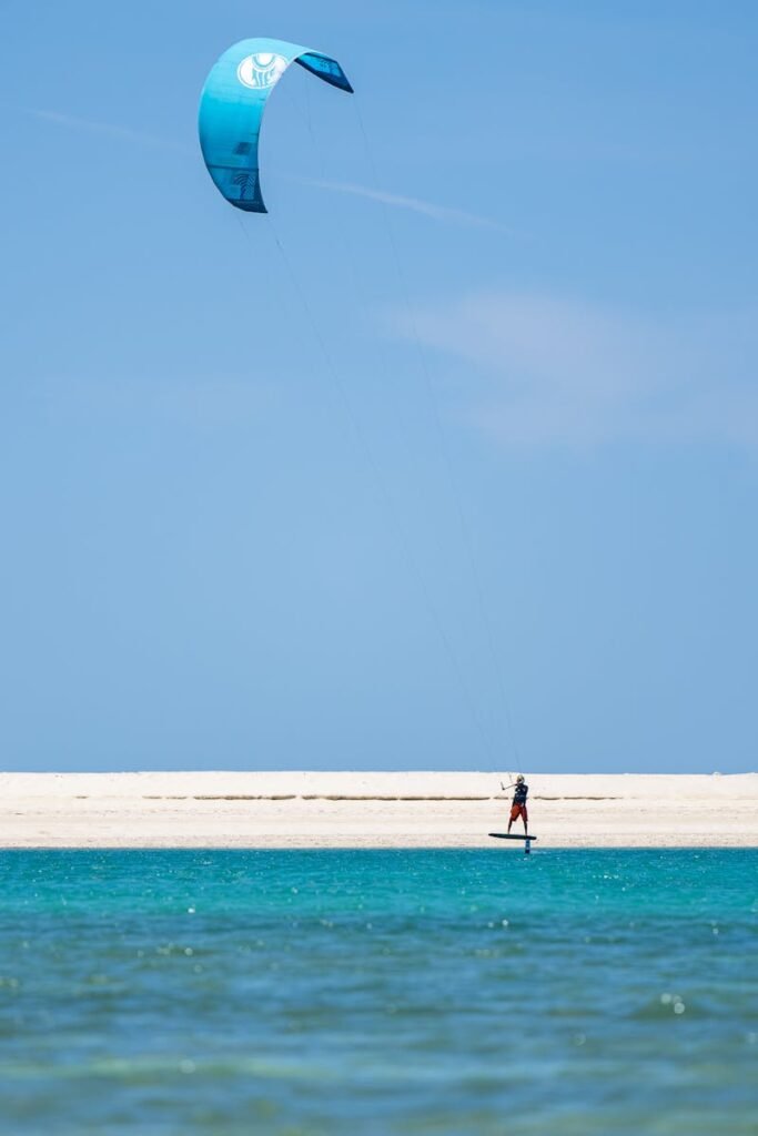 Experience thrilling kite surfing in Dubai with a clear blue sky and vibrant sea.