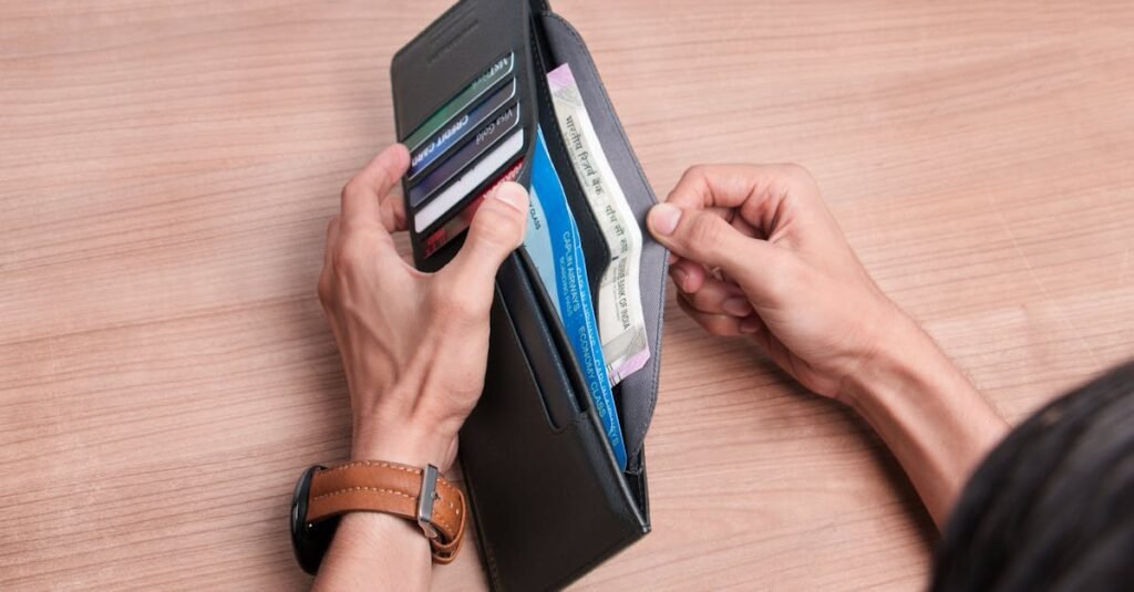Close-up of a person managing a wallet with cash and cards on a wooden table.