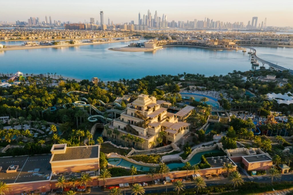 A breathtaking aerial shot of Palm Jumeirah with the Dubai skyline in the backdrop, featuring serene waters and lush greenery.