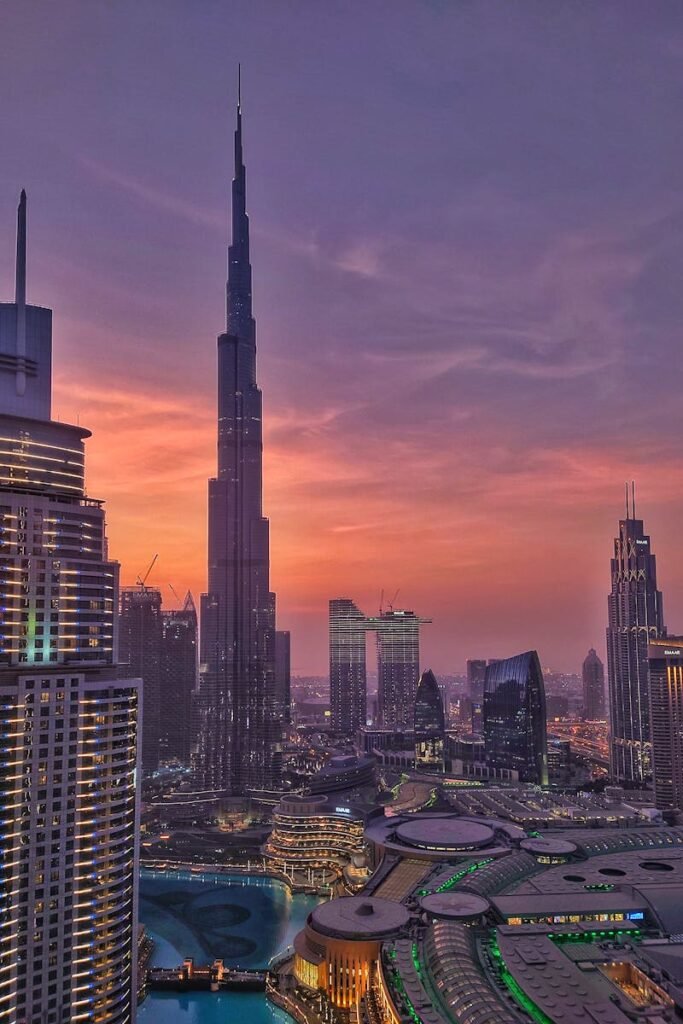 Dramatic sunset view of Dubai skyline featuring the iconic Burj Khalifa towering over the city.